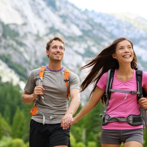 Hotel Sonnenhof Couple hiking in the mountains holding hands and smiling with backpacks