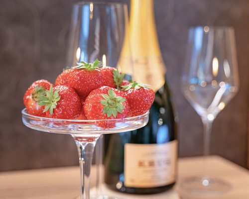 Hotel Sonnenhof Erdbeeren in Glas mit Champagnerflasche und zwei Gläsern im Hintergrund