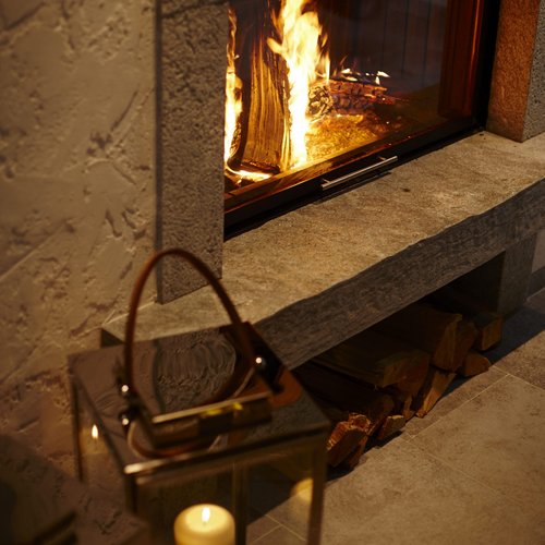 Hotel Sonnenhof Gemütlicher Holzofen mit brennendem Feuer und Kerzen im Glaslaterne