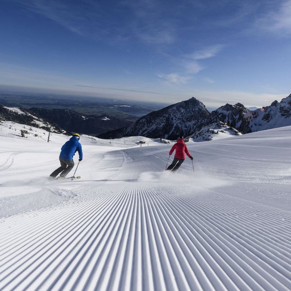 Hotel Sonnenhof Zwei Skifahrer auf frisch gespurter Piste in den Bergen bei klarem Himmel