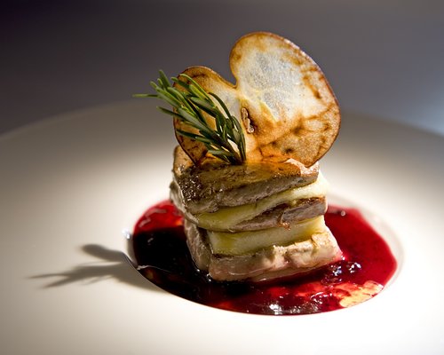 Hotel Sonnenhof Gourmetgericht mit Fleisch, Apfelscheiben, Rosmarin und roter Sauce auf weißem Teller