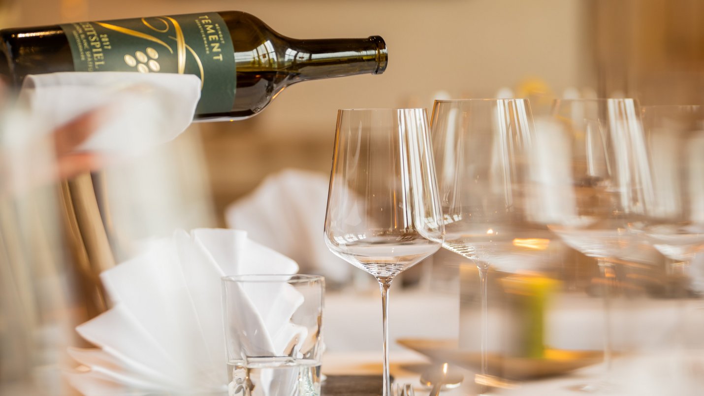 Hotel Sonnenhof Wein wird in ein Glas an festlich gedecktem Tisch eingeschenkt