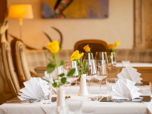 Hotel Sonnenhof Elegant table setting with white napkins and yellow roses in a restaurant