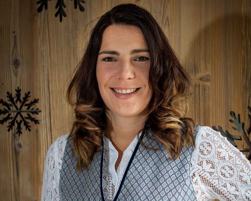 Hotel Sonnenhof Frau in traditioneller Tracht vor Holzwand mit Schneeflocken-Dekor