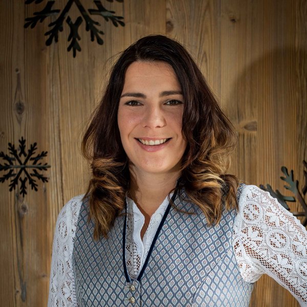 Hotel Sonnenhof Frau in traditioneller Tracht vor Holzwand mit Schneeflocken-Dekor