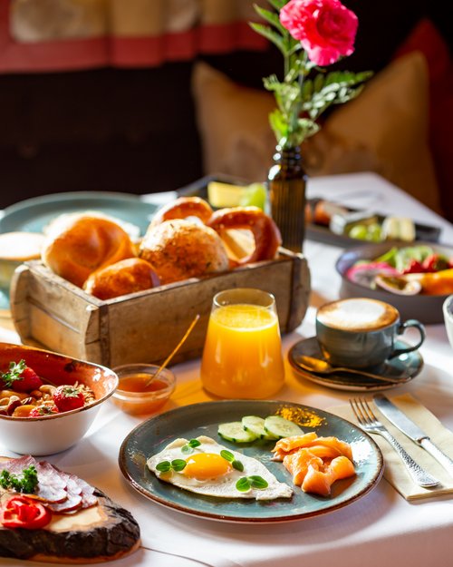 Hotel Sonnenhof Breakfast table with fried egg, salmon, bread rolls, orange juice, and coffee