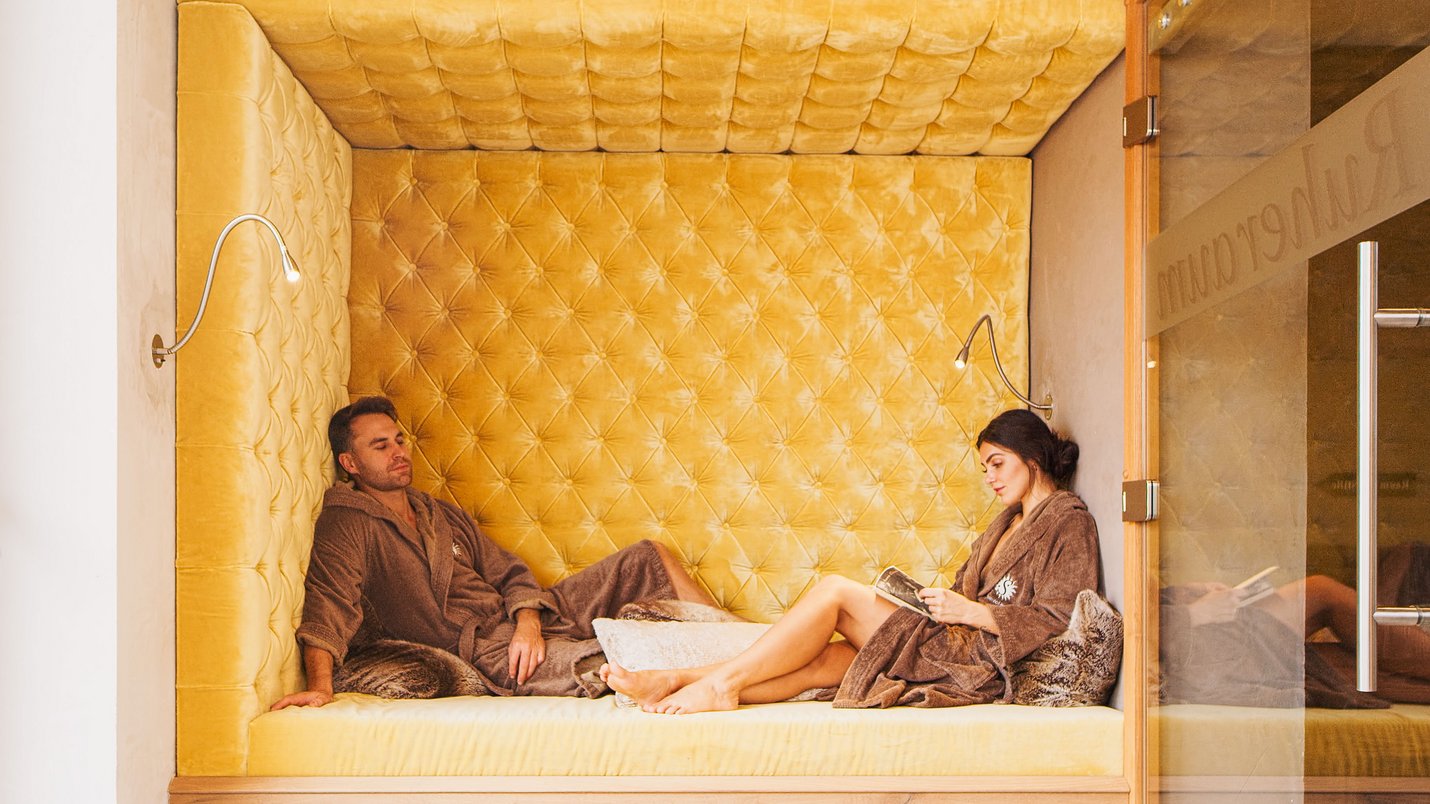 Hotel Sonnenhof Paar in braunen Bademänteln entspannt in gepolstertem Ruhebereich