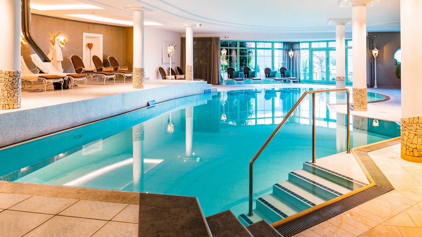 Hotel Sonnenhof Hallenbad mit Liegestühlen und großen Fenstern in einem Wellnessbereich