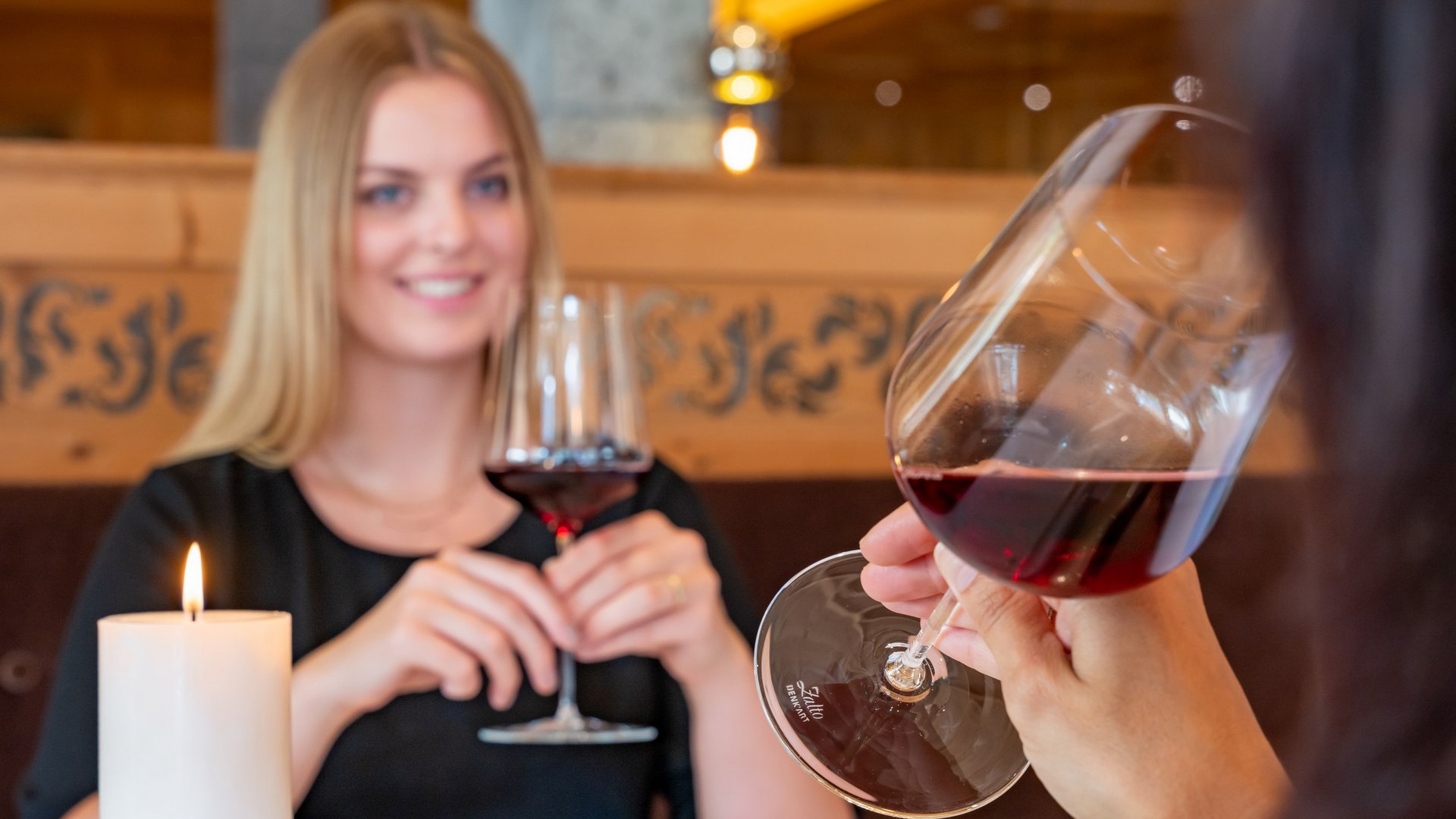 „das Müllers“ Grän – 2-Hauben À-la-carte-Restaurant im Tannheimertal Zwei Personen stoßen mit Weingläsern bei einem gemütlichen Abendessen mit Kerzenlicht an