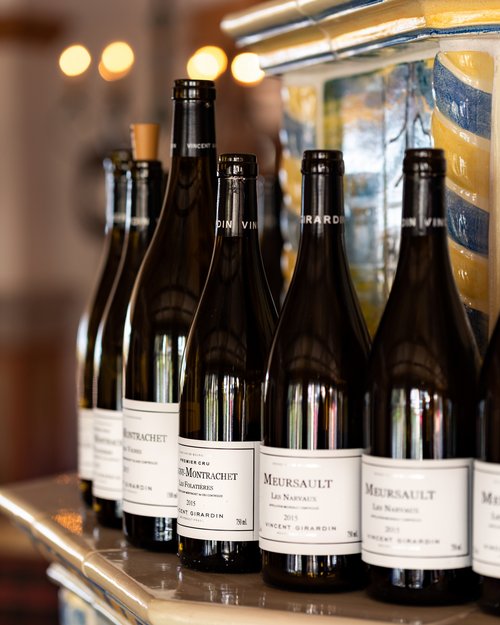 Hotel Sonnenhof Several wine bottles with white labels displayed on a decorated tile shelf
