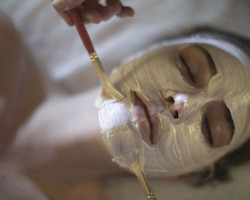 Hotel Sonnenhof Person mit geschlossenen Augen bekommt eine weiße Gesichtsmaske mit Pinsel aufgetragen
