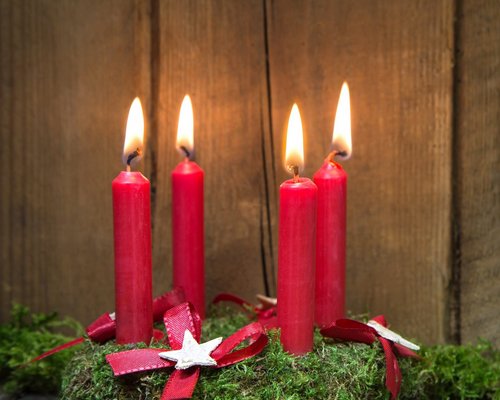 Hotel Sonnenhof Adventskranz mit vier roten brennenden Kerzen auf Holz und Moos