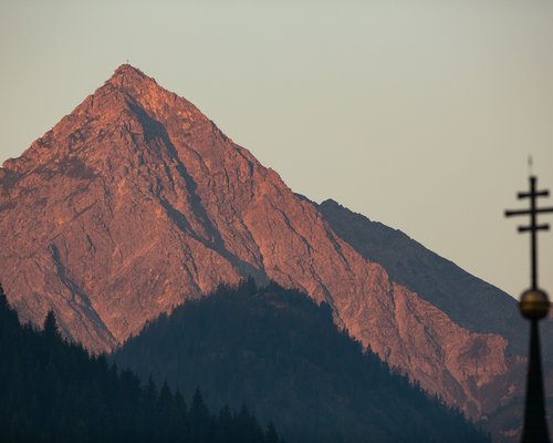 Hotel Sonnenhof Berggipfel im Sonnenuntergang mit Kreuz und Kirchenkreuz im Vordergrund