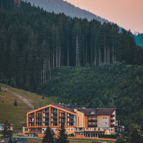 Hotel Sonnenhof Alpine hotel in front of pine forest and mountains at sunset