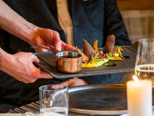 Hotel Sonnenhof Waiter serving a creatively presented dish on a black plate in a restaurant