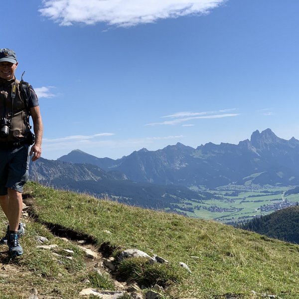 Hotel Sonnenhof Mann mit Kamera wandert auf Bergpfad mit Alpenpanorama im Hintergrund