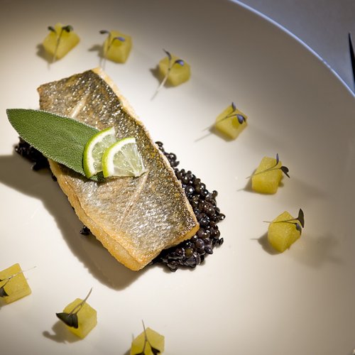 Hotel Sonnenhof Gebratenes Fischfilet auf schwarzen Linsen mit Zitronenscheiben und Kräutern
