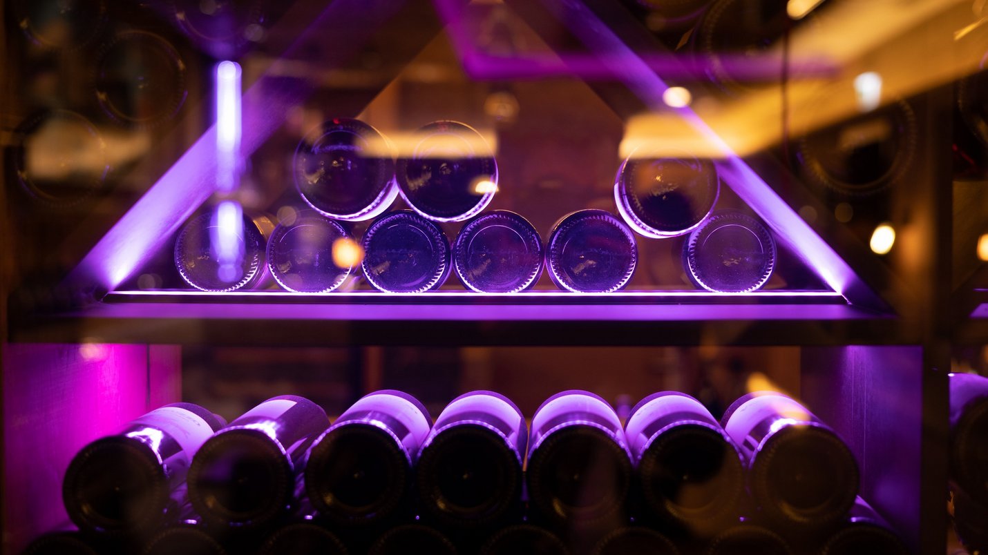 Hotel Sonnenhof Weinflaschen in einem Regal mit violetter Beleuchtung