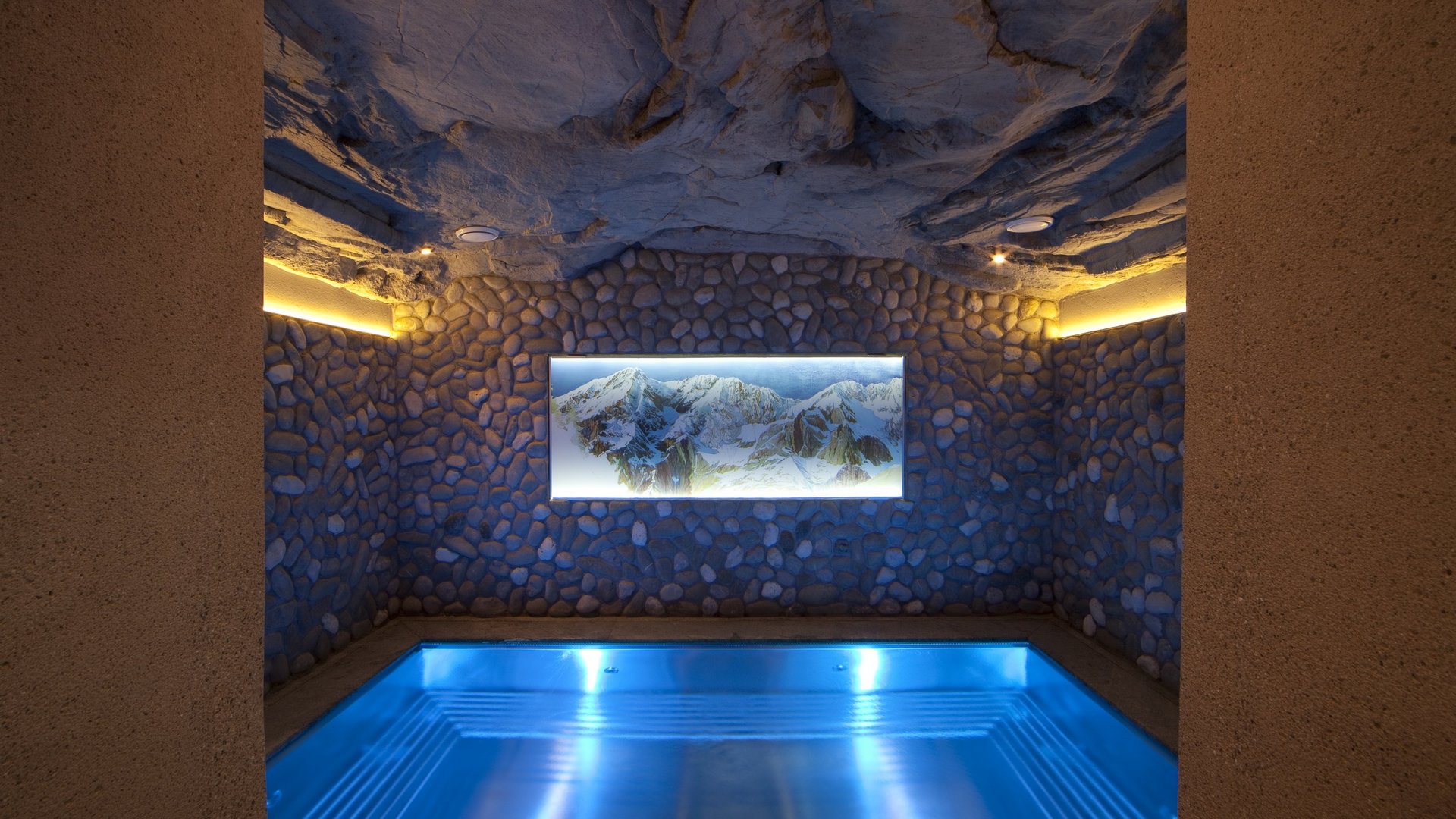 Hotel Sonnenhof Heated indoor pool with stone walls and mountain painting on the wall