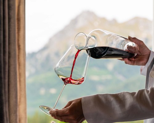 Hotel Sonnenhof Roter Wein wird in ein Weinglas vor Bergkulisse eingeschenkt