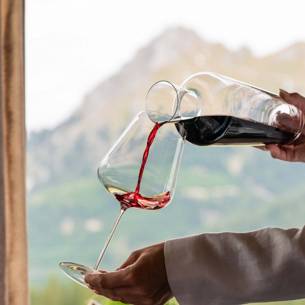 Hotel Sonnenhof Roter Wein wird in ein Weinglas vor Bergkulisse eingeschenkt