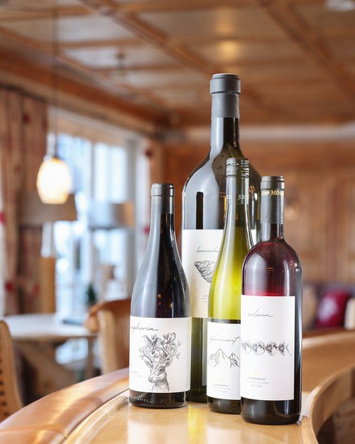 Hotel Sonnenhof Four wine bottles with elegant labels on a wooden counter in a restaurant