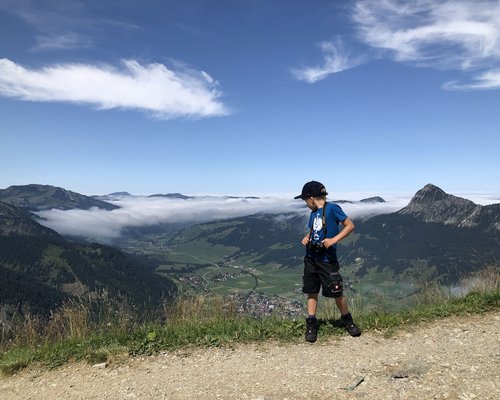 Hotel Sonnenhof Junge mit Kamera steht auf Bergpfad mit Blick auf Tal und Wolken