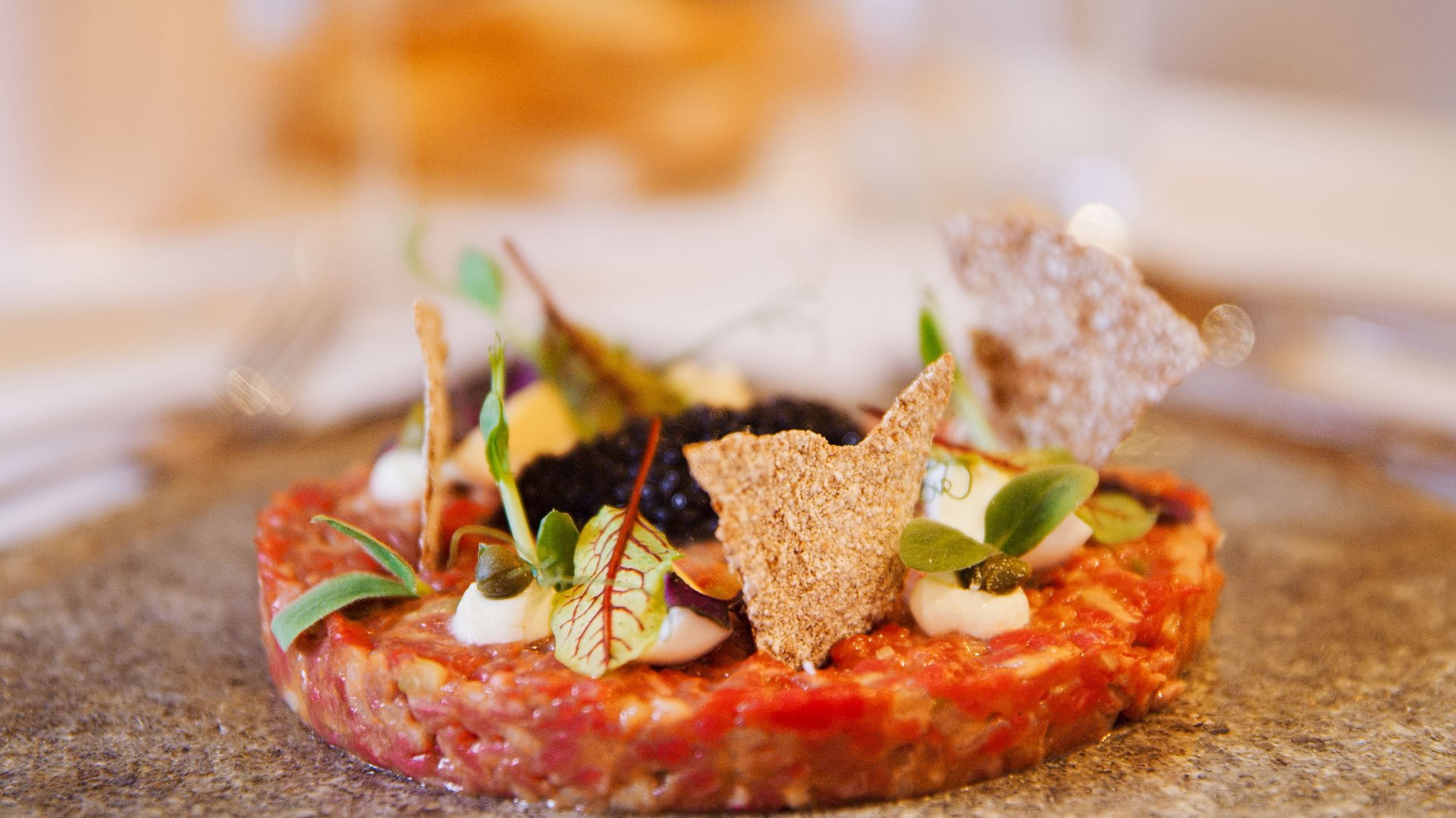Hotel Sonnenhof Close-up of gourmet steak tartare with cream, greens, and crisp garnishes