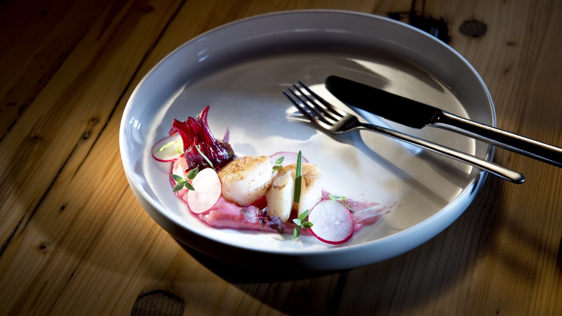 Hotel Sonnenhof Seared scallops with radishes and red sauce on a white plate