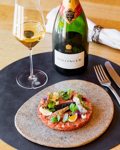 Hotel Sonnenhof Beef tartare with egg, caviar, herbs, and a glass and bottle of Bollinger champagne