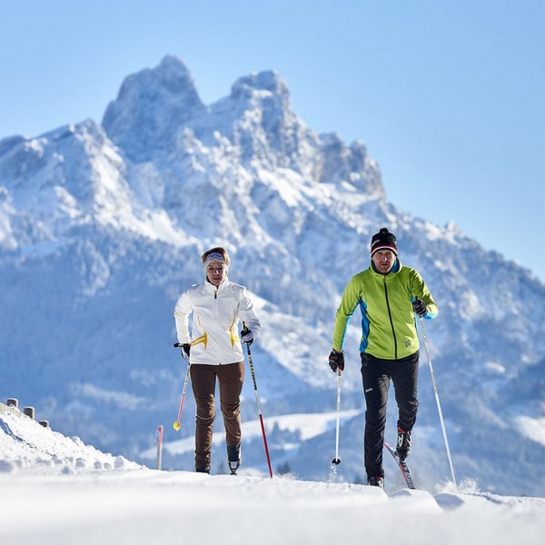 Hotel Sonnenhof Zwei Langläufer in Winterkleidung vor schneebedeckten Bergen bei klarem Himmel