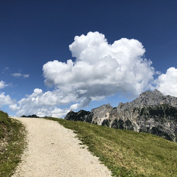 Hotel Sonnenhof Wanderweg auf einem Berg mit Wolken und Gipfeln im Hintergrund